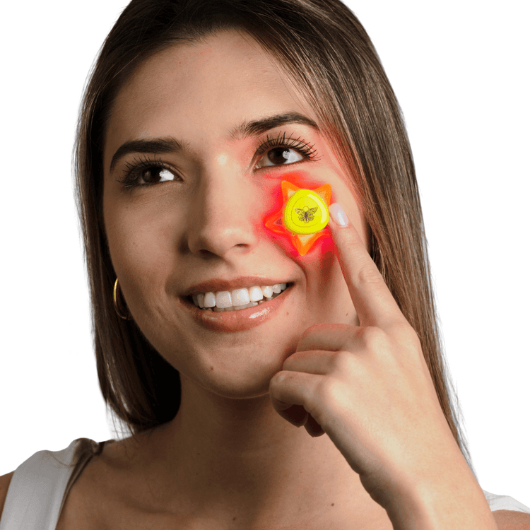 Star-shaped Metamorphosis LED light therapy device under her eye, which emits red light for targeted anti-aging, wrinkle reduction, and skin rejuvenation treatments