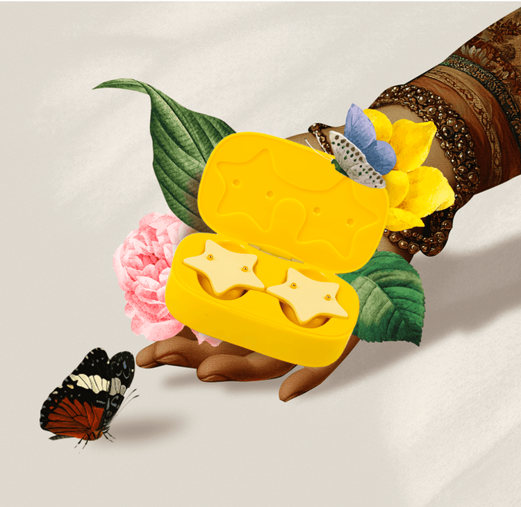 Metamorphosis Artistic shot of a hand holding an open yellow star-shaped case with two Metamorphosis Superstar Pimple Patches inside, decorated with butterflies and flowers