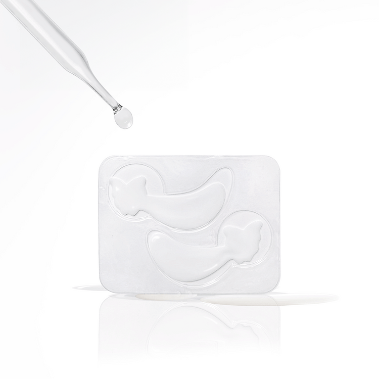 Metamorphosis A clear dropper dispensing a drop of serum over two white eye masks in a plastic tray, illustrating the application method for eye masks.