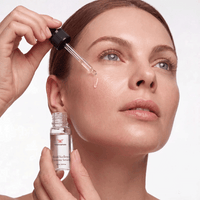 Model applying Metamorphosis SkinEXcellence Exosome Serum to her cheek using a dropper for anti-aging skincare and cell renewal benefits.