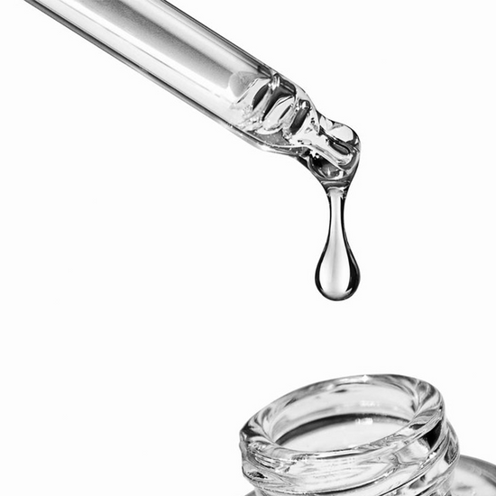 Metamorphosis A close-up studio shot of a clear glass dropper with a single drop of serum or liquid falling towards an open skincare bottle, highlighting product texture and application